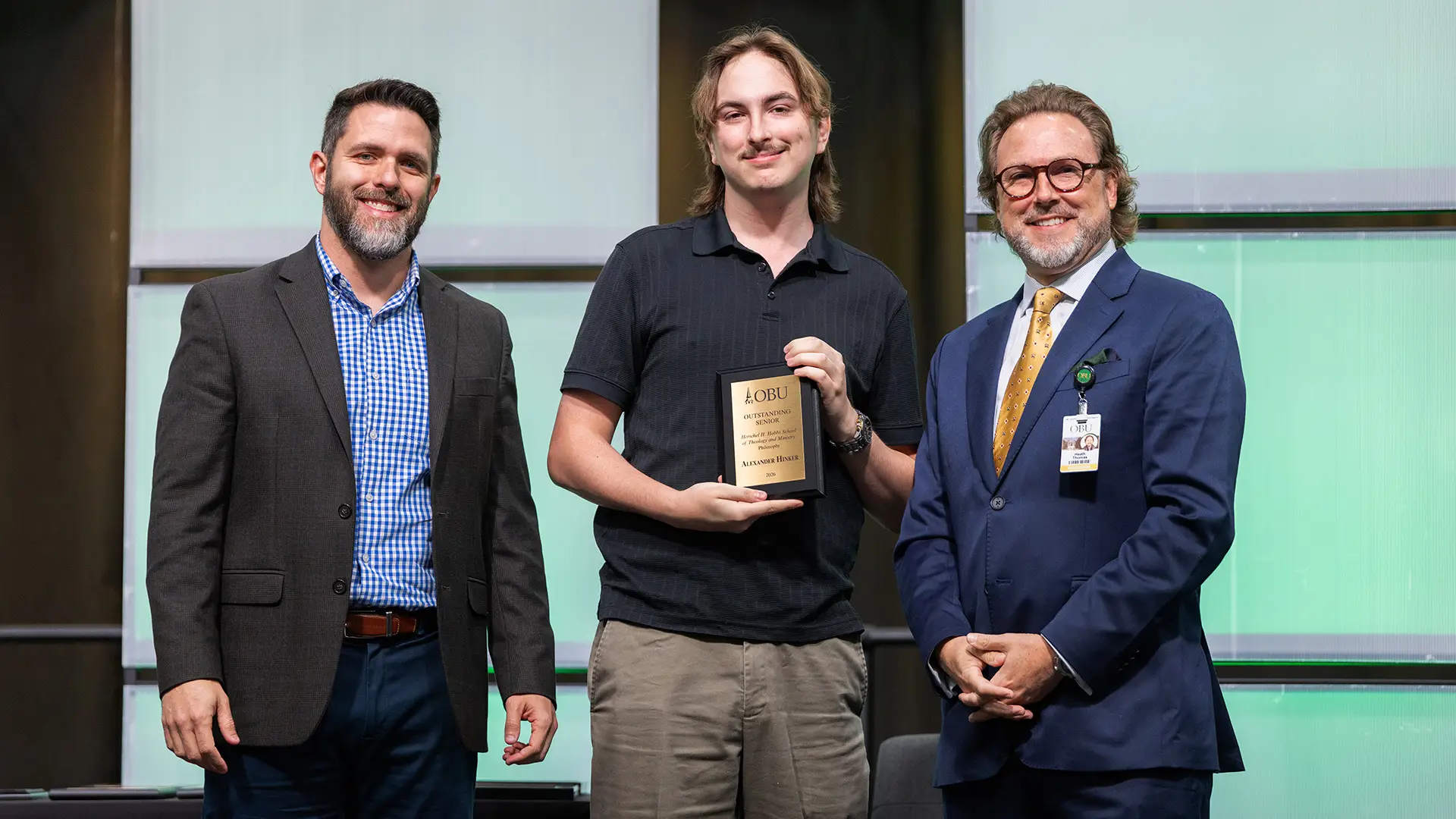 Dr. Brandon D. Smith, chair of the Herschel H. Hobbs School of Theology and Ministry, left, and OBU President Dr. Heath A. Thomas, right, presented the Outstanding Senior Award in philosophy from the Herschel H. Hobbs School of Theology and Ministry to Alexander Hinker, center.