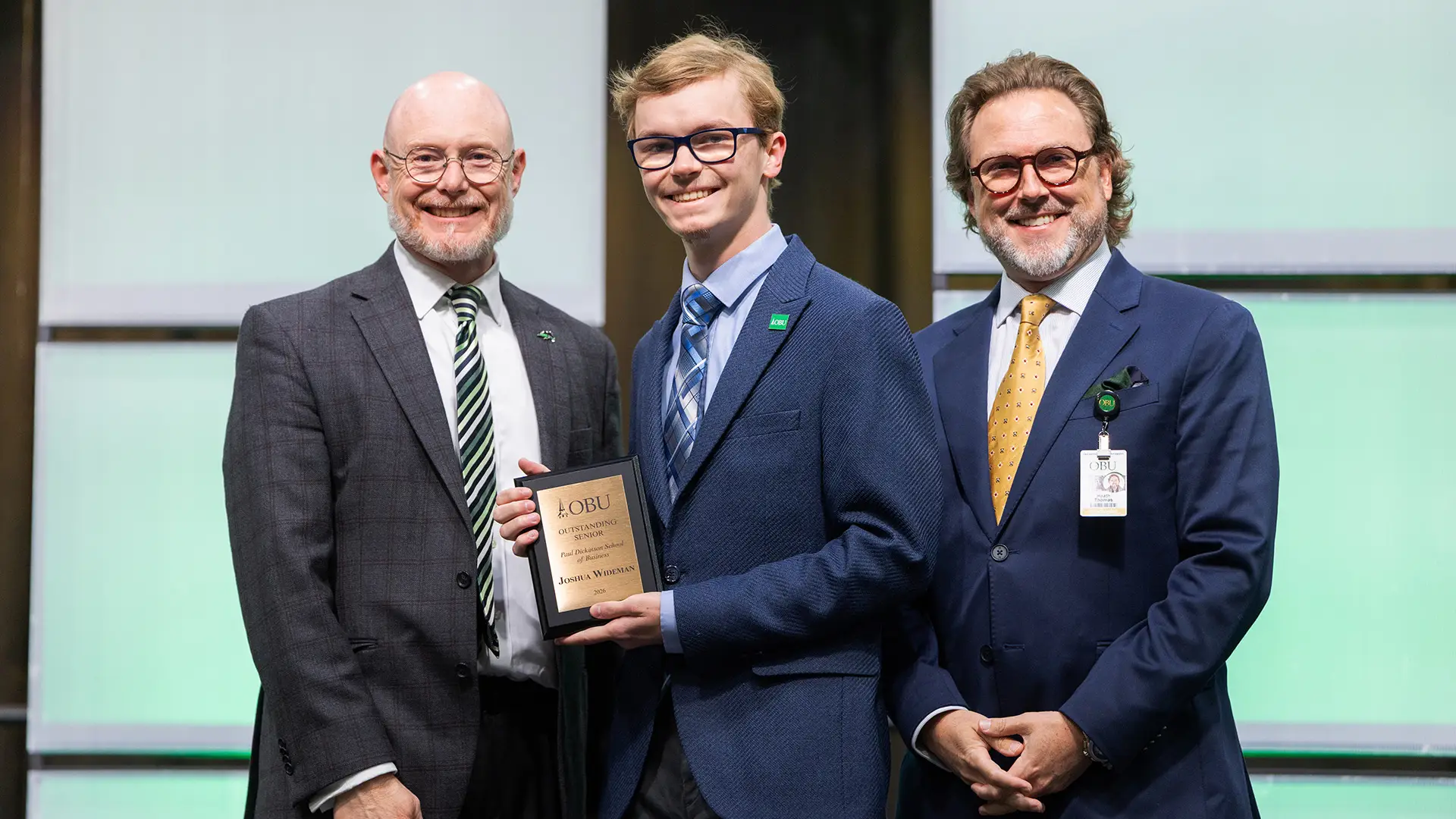 Dr. David Houghton, chair of the School of Business, left, and OBU President Dr. Heath A. Thomas, right, presented the Outstanding Senior Award from the Paul Dickinson School of Business to Joshua Wideman, center.