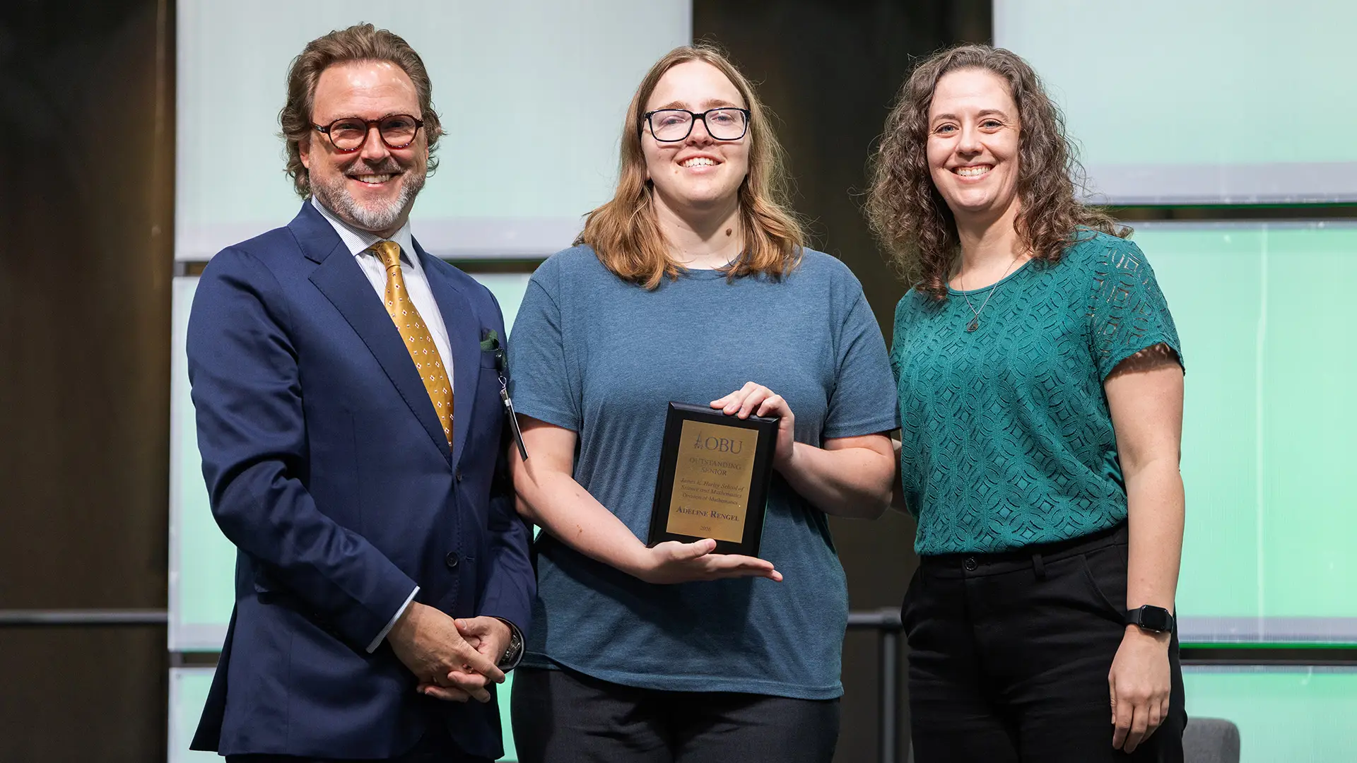 OBU President Dr. Heath A. Thomas, left, and Dr. Cherith Tucker, chair of the Division of Mathematics, right, presented the Outstanding Senior Award from the Division of Mathematics to Adeline Rengel, center.